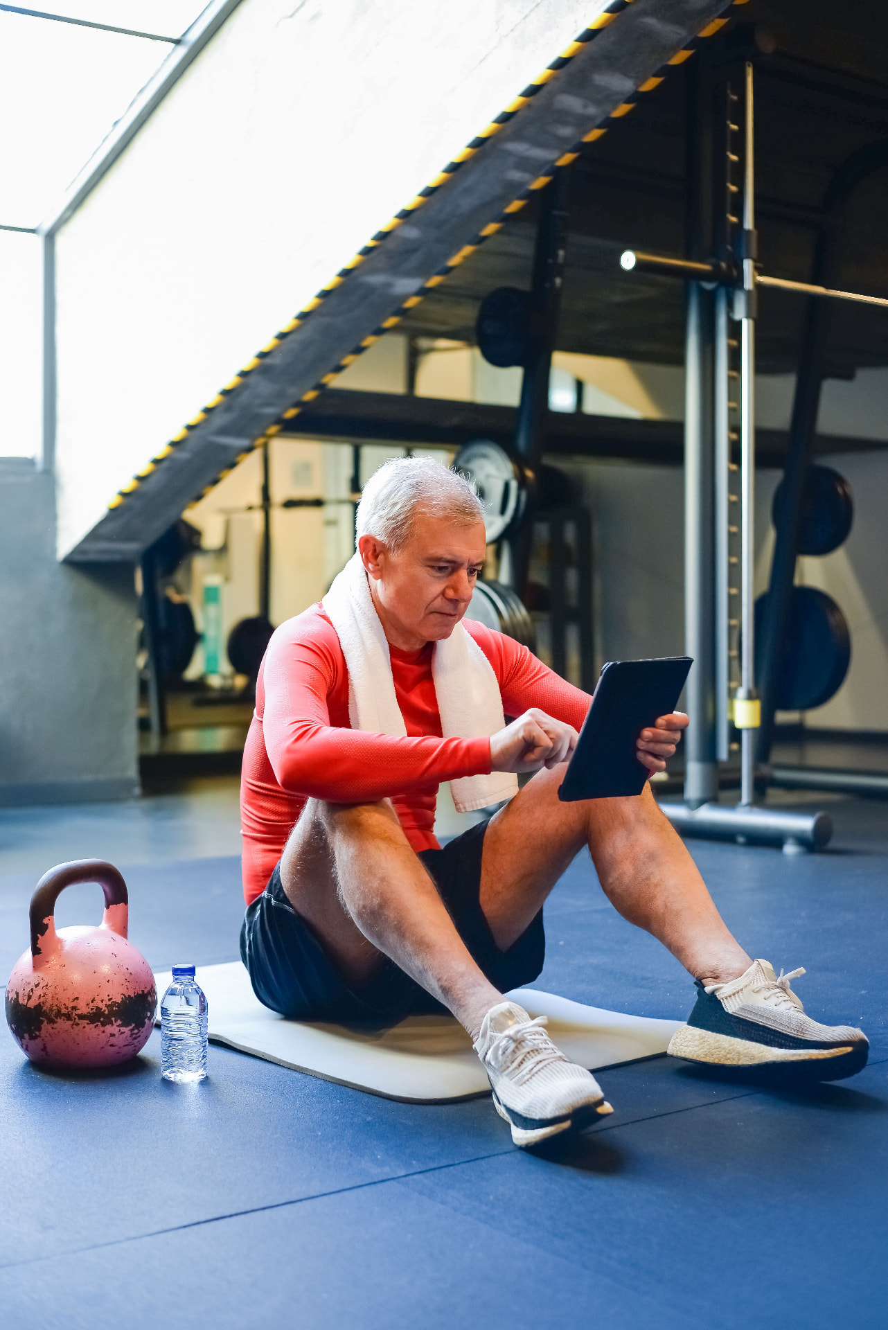 Older man in a gym reviewing his health results on a tablet