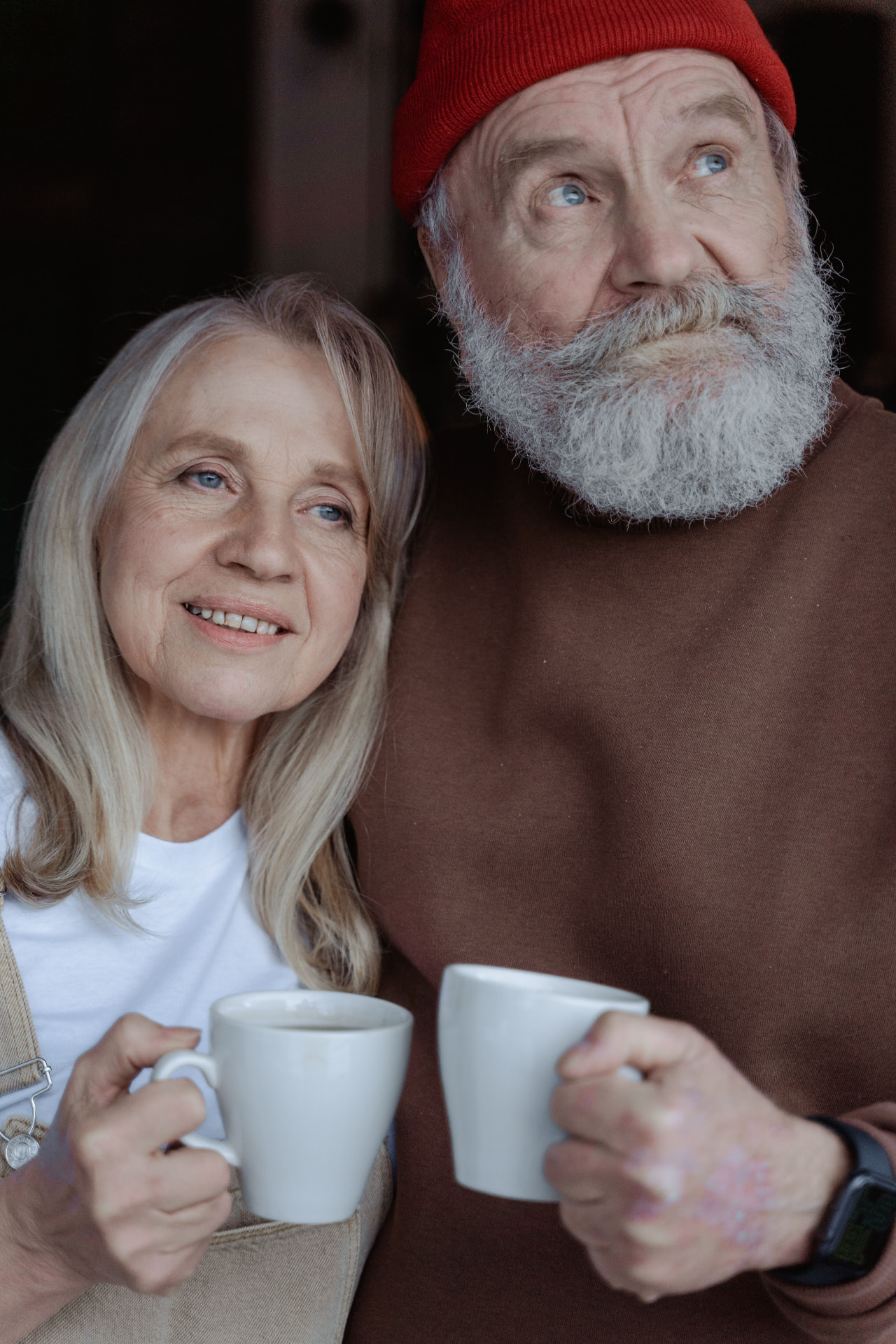 Older couple smiling together while holding mugs of coffee