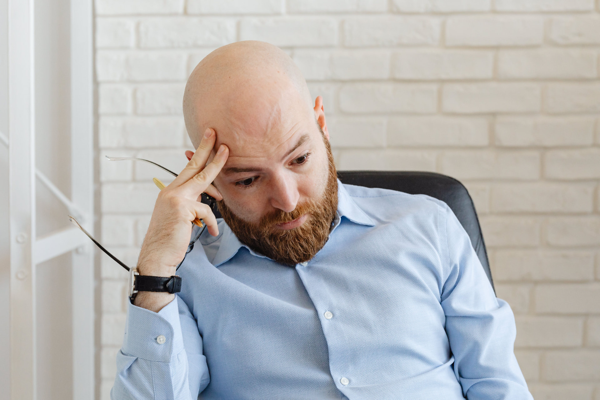 Man looking tired and stressed, resting his head in his hand